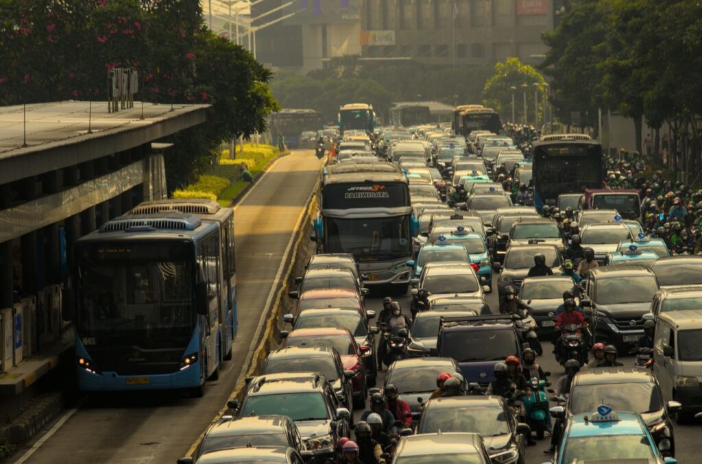 Heavy traffic in a city with cars, buses, and motorcycles on a crowded road.