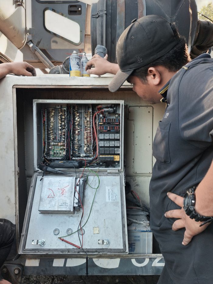 A technician examines an outdoor electrical panel during daylight, highlighting maintenance procedures.