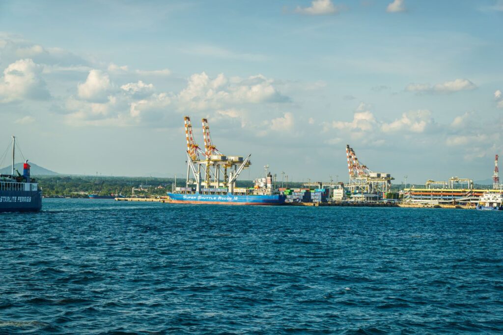 A bustling cargo port with ships and cranes under a clear blue sky, ideal for stock photos.
