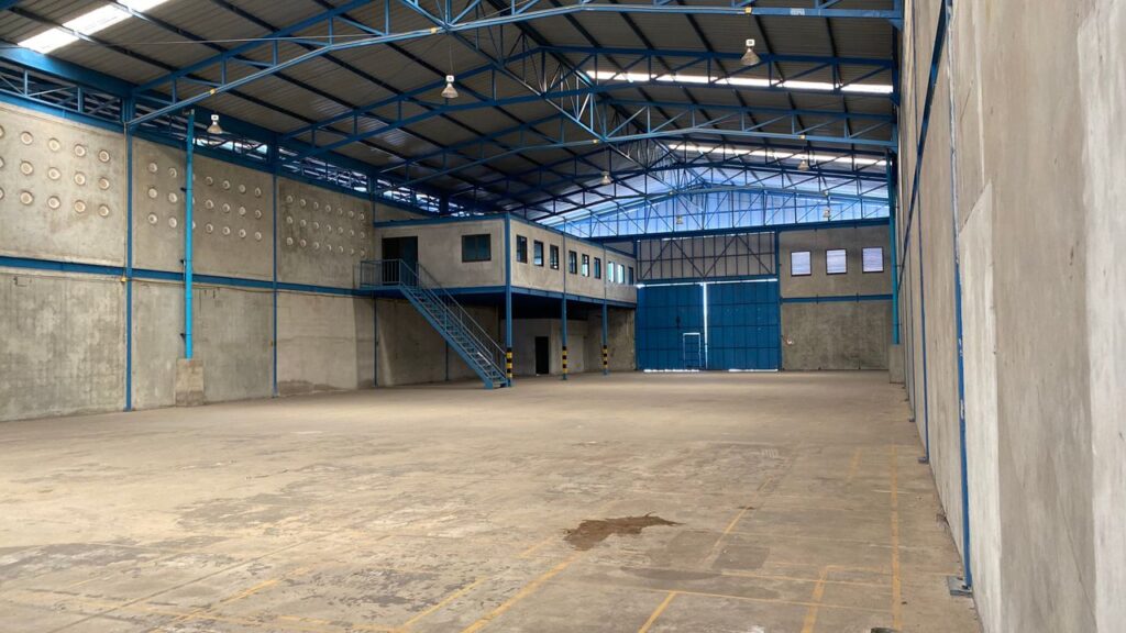 Empty warehouse with blue steel frame and concrete walls in Bangkok.