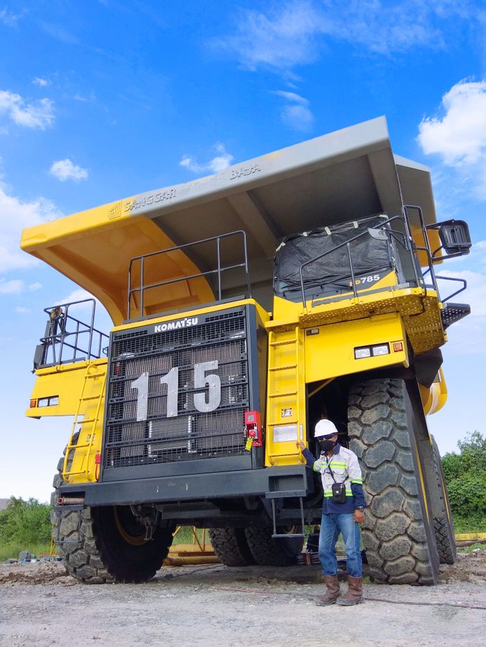 A large Komatsu mining truck with a worker standing beside it in Indonesia.