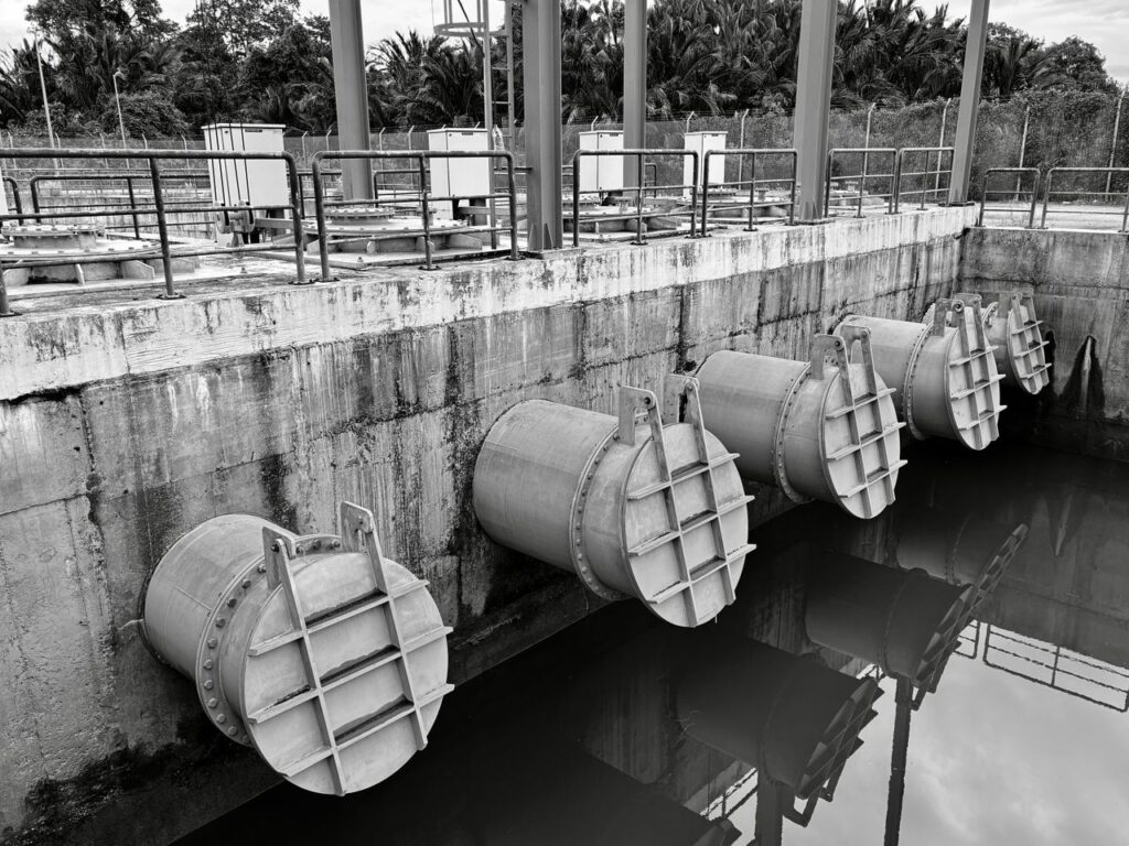 Monochrome image of large industrial water pipes with valves.